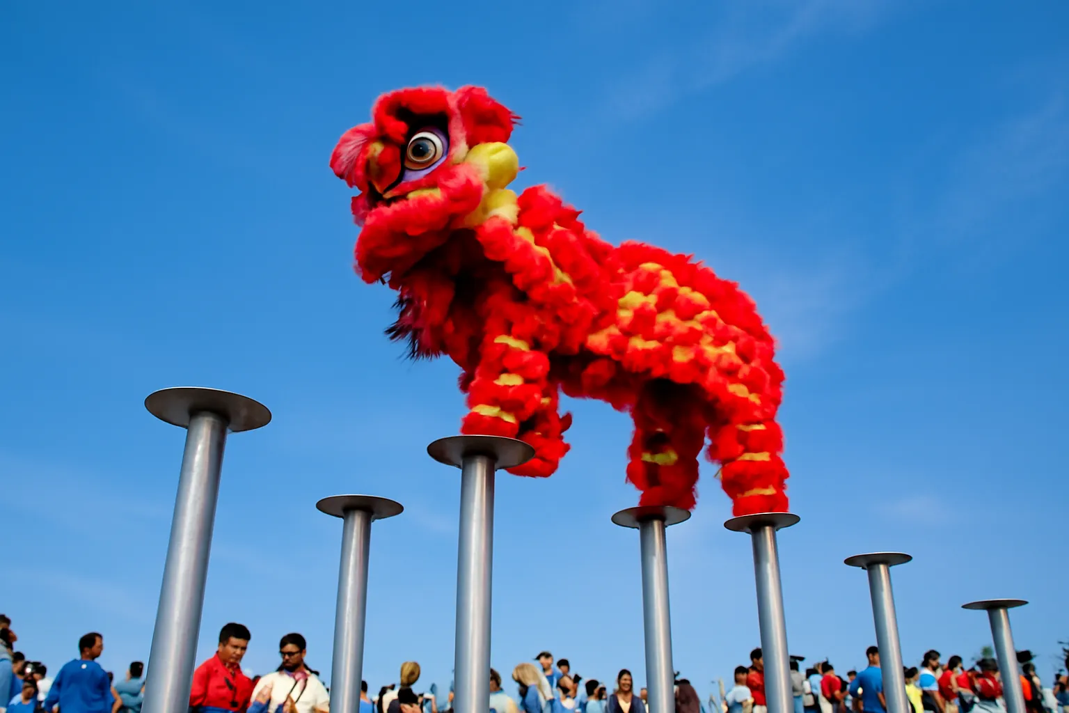 Con lân đỏ vàng đứng trên đỉnh cột sắt cao giữa trời xanh, người xem phía dưới